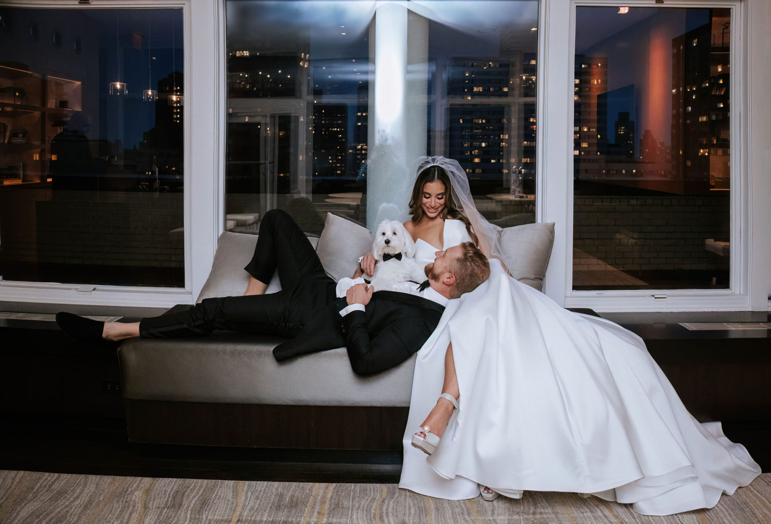 elegant-couple-relaxing-with-handsome-white-dog-with-a-black-tie.