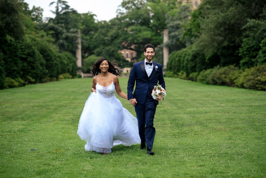 Couple walking through the Osprey Garden at Brooklyn Botanical Garden in New York City surrounded by lush greenery and pillars.