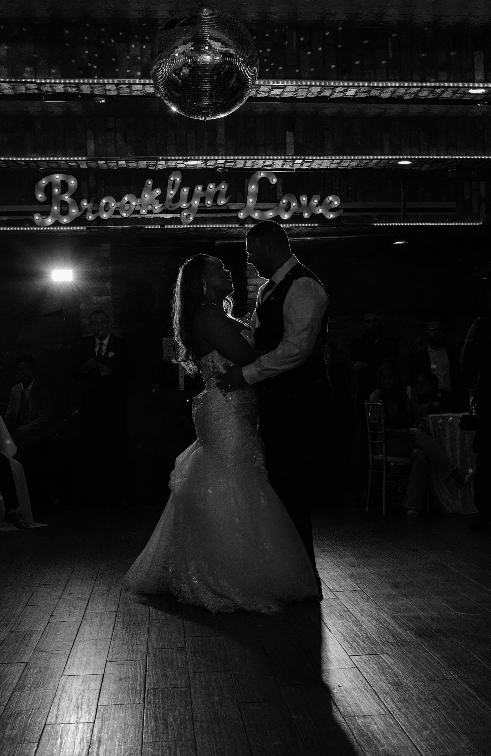 Bride and groom first dance at the Deity's Cellar with the Brooklyn Love sign lit in the background.